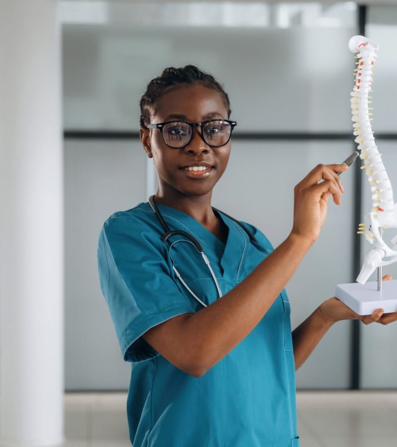 Human spine model, teaching and showing. Female doctor is indoors in modern room.