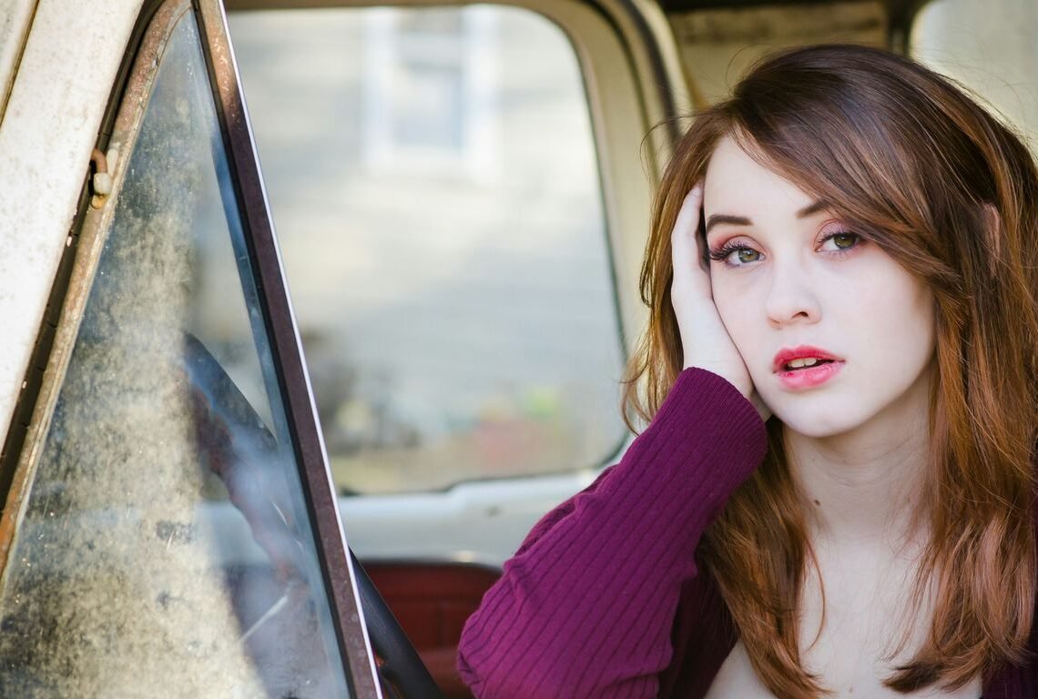 woman in purple cardigan sitting inside car during daytime