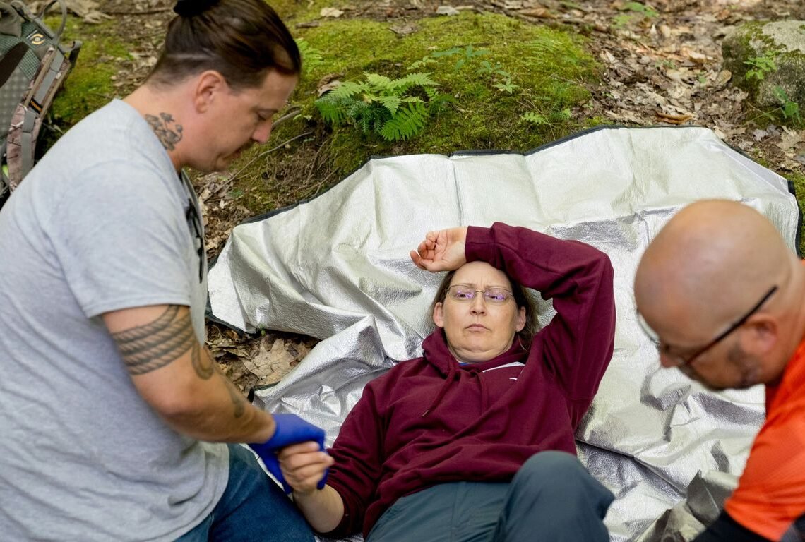 Paramedics attend to an injured person in the woods.