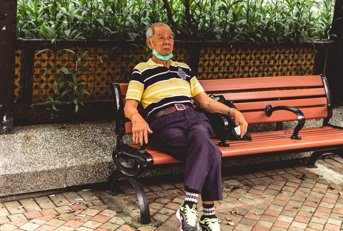 woman in blue and yellow stripe shirt sitting on brown bench